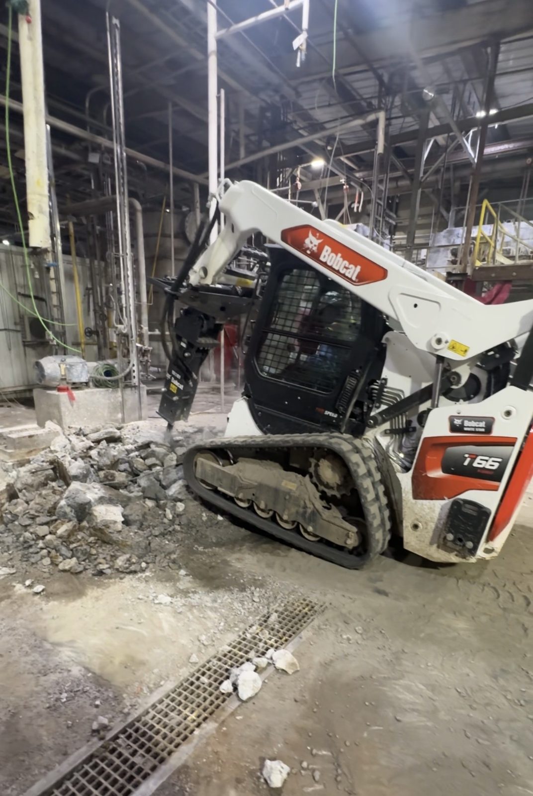 Skid steer breaking concrete inside an industrial facility